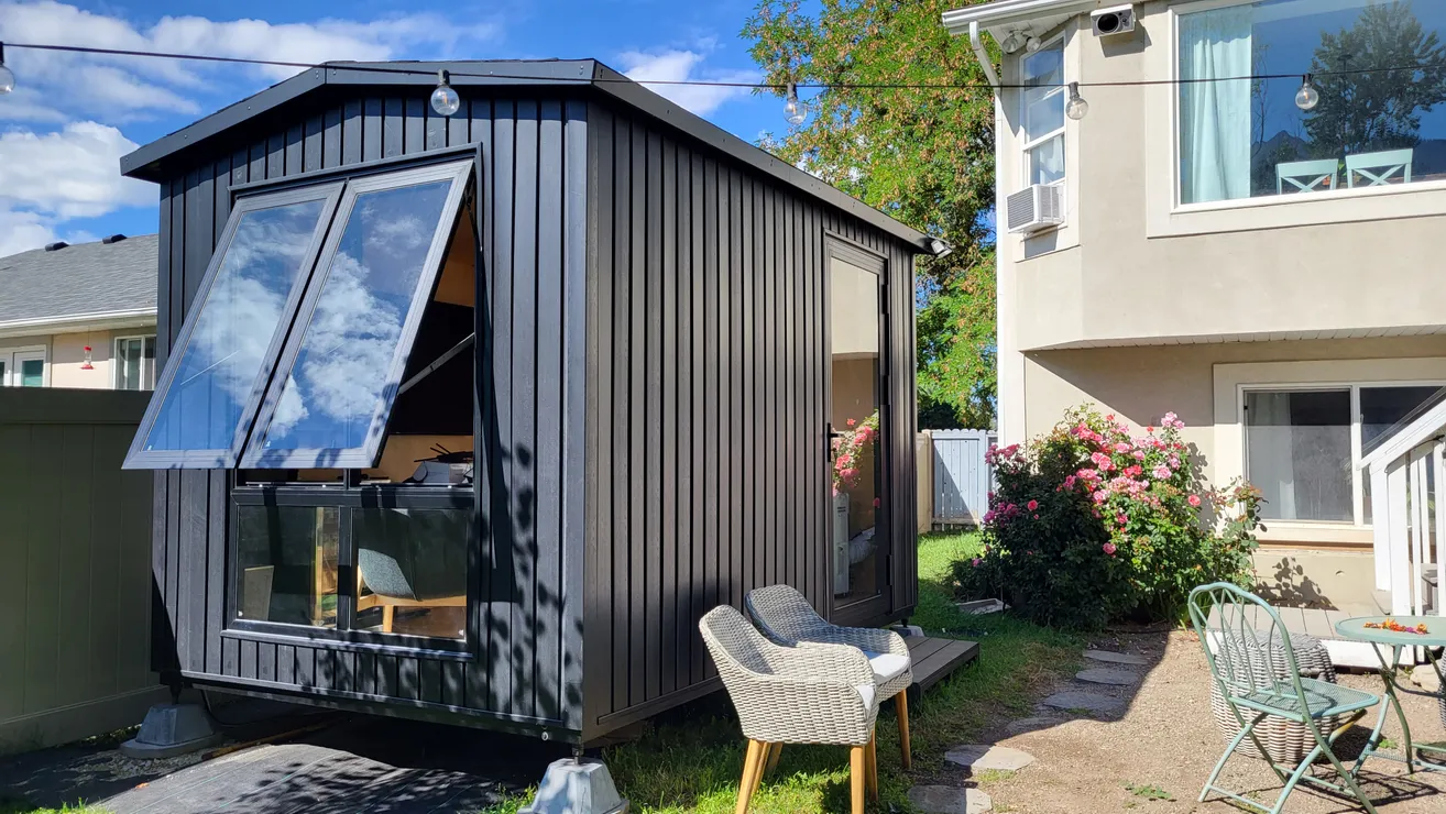 Black WorkPod with an open awning window beside a patio