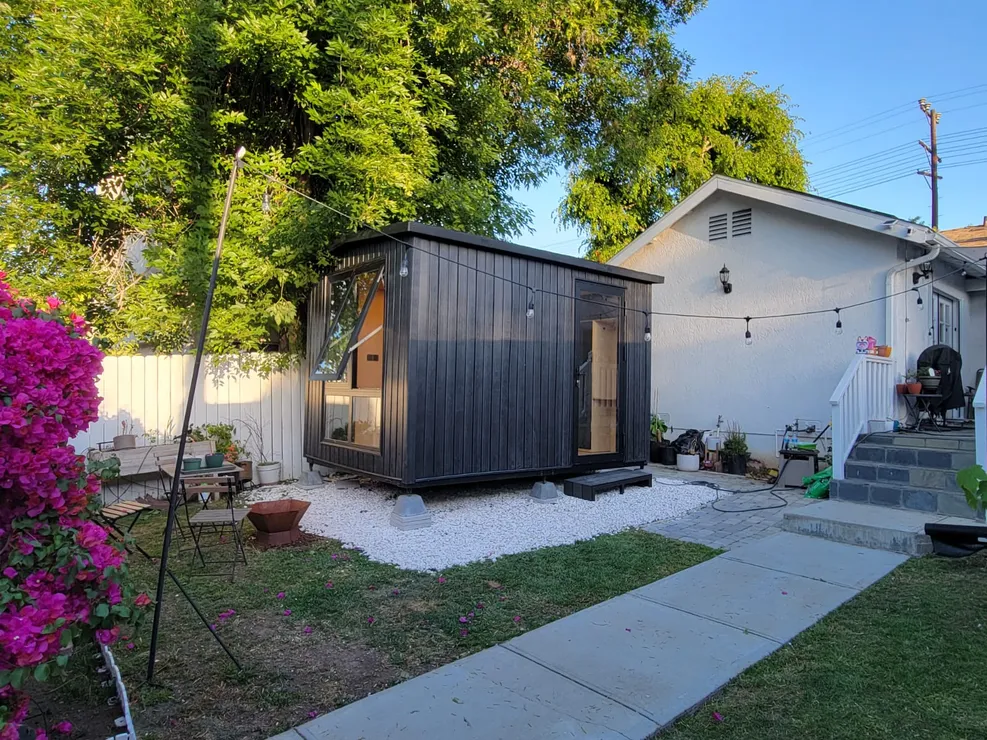 Black WorkPod in a backyard with pink bougainvillea