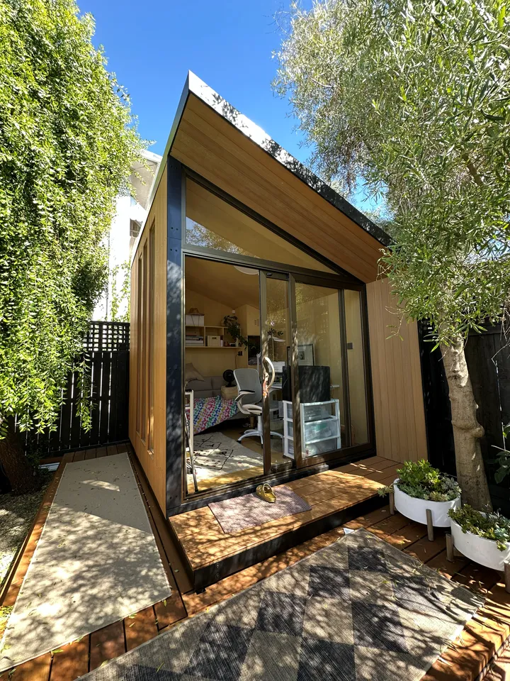 Wood WorkPod home office with sliding glass doors under an olive tree