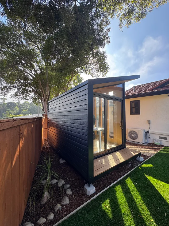 Black WorkPod with a deck in a side yard with artificial turf