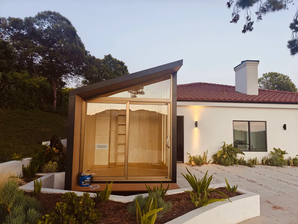 Wood-finish WorkPod with glass doors next to a white house