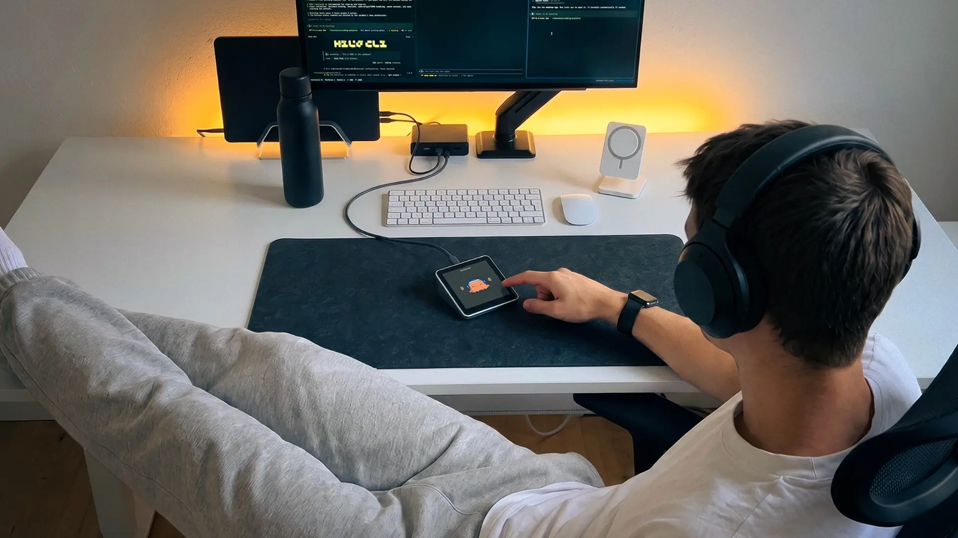 Developer tapping a Harness Pro desk display beside a desktop monitor