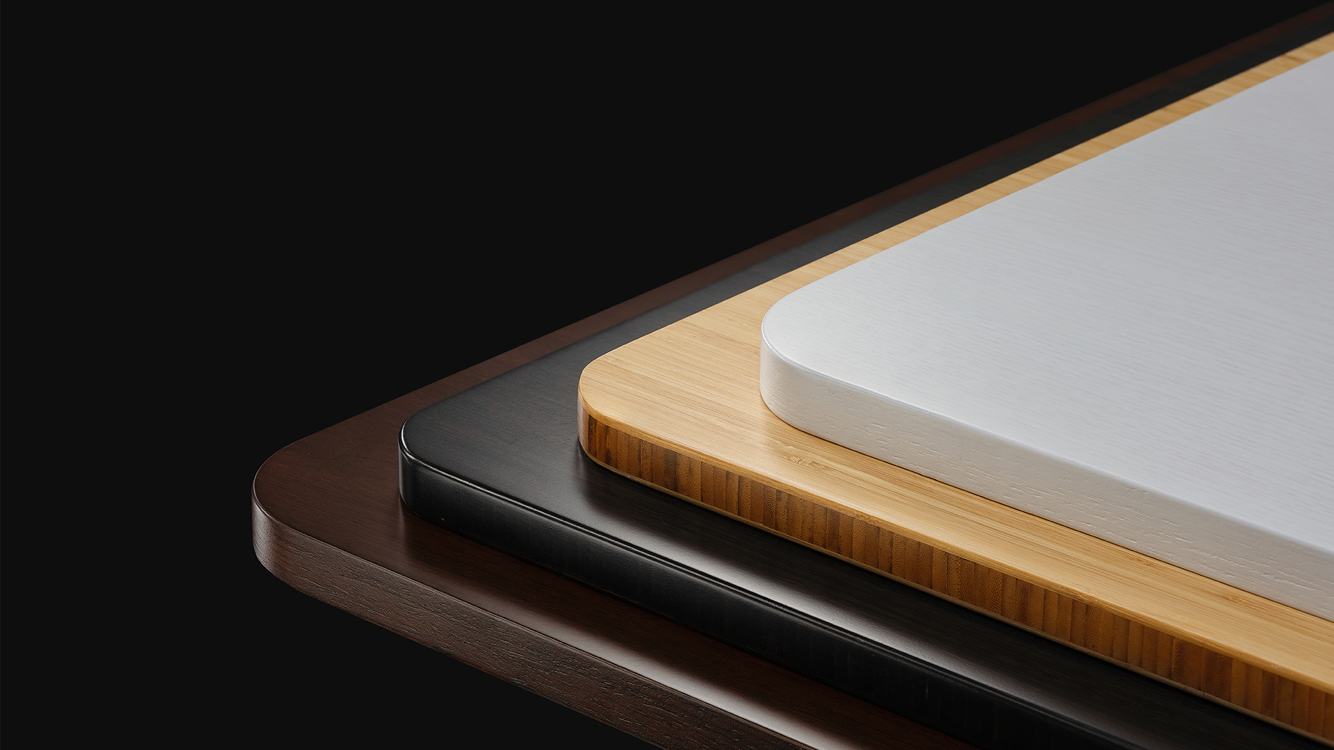Corners of Autonomous Desk Surface tops stacked in several finishes